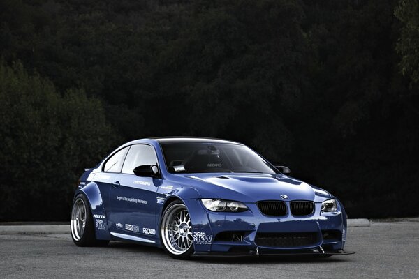 Синяя спортивная BMW на фоне леса