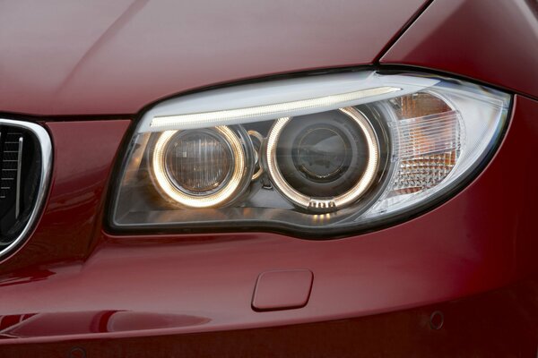 The headlight of a large, red car close-up