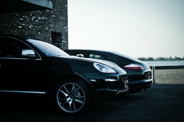 A chic black Porsche Cayenne parked in front of a brick building