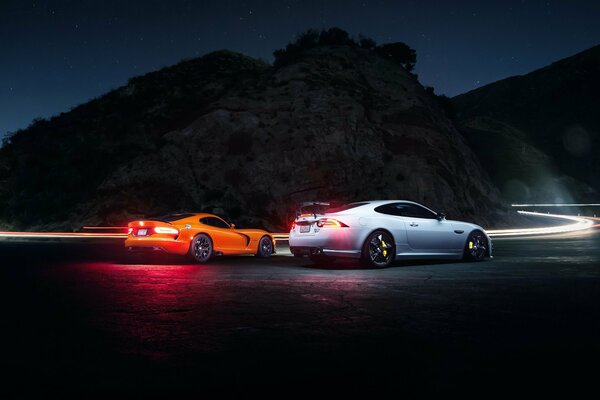 Autos Dodge et Jaguar sur la route de nuit.