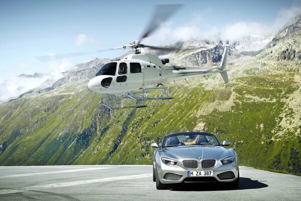 Ein Hubschrauber und ein grauer BMW in den Bergen