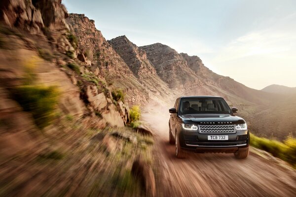 Black land rover on a dirt track surrounded by rocks