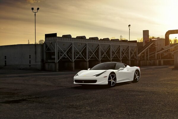 Weißer Ferrari-Rennwagen auf Fabrikhintergrund bei Sonnenuntergang