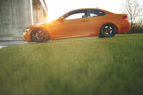 Orange BMW near the lawn in the sun