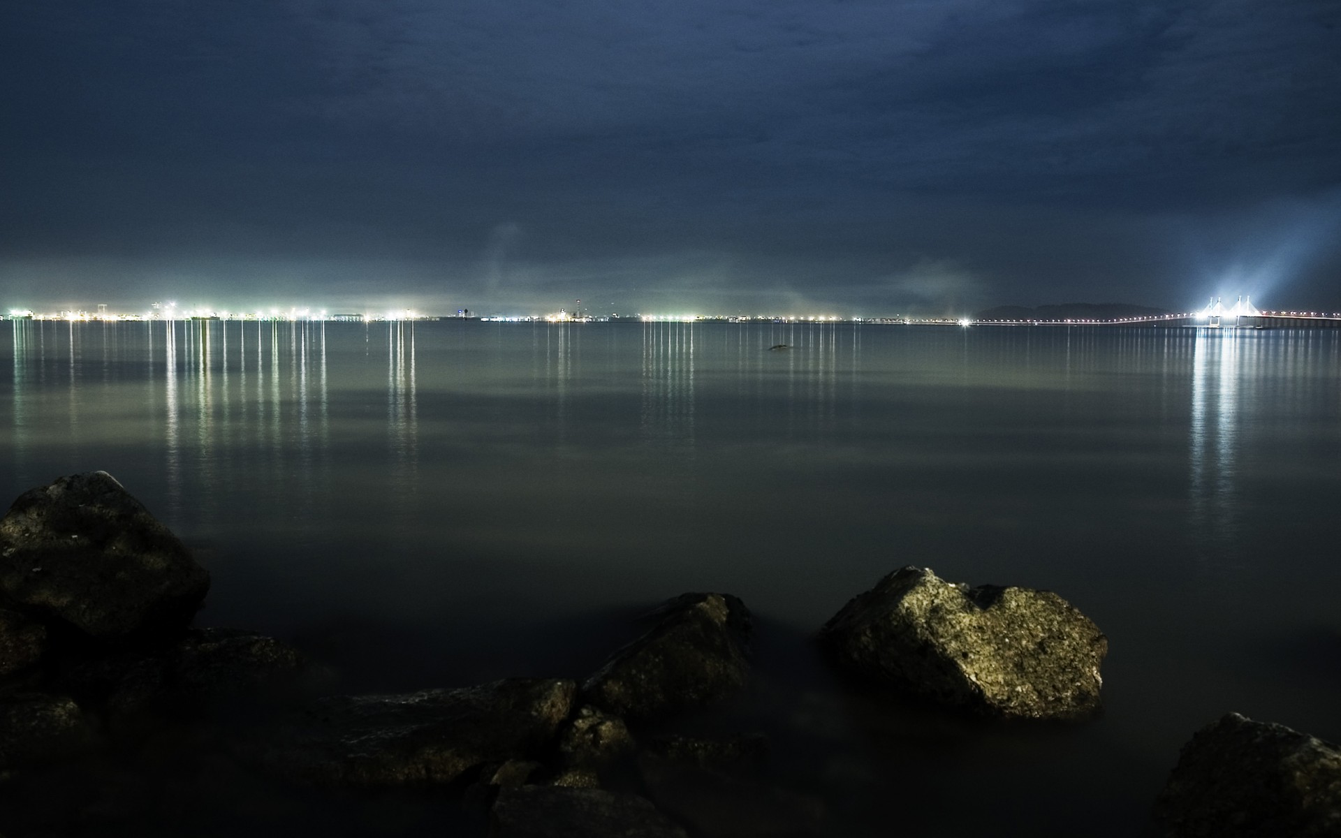 piedras agua luces de la ciudad reflexión