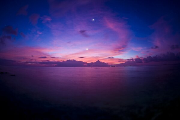 Puesta de sol púrpura por la noche en la orilla del mar