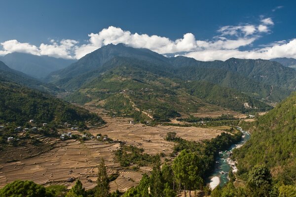 Village avec des champs et une rivière dans les montagnes