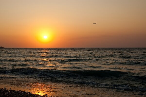 Coucher de soleil sur la mer avec un avion dans le ciel