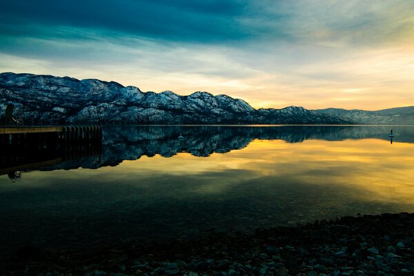 Puesta de sol en el fondo de las montañas y el lago