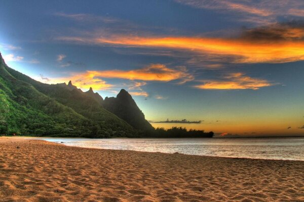 La playa al atardecer con el fondo de las montañas y el mar