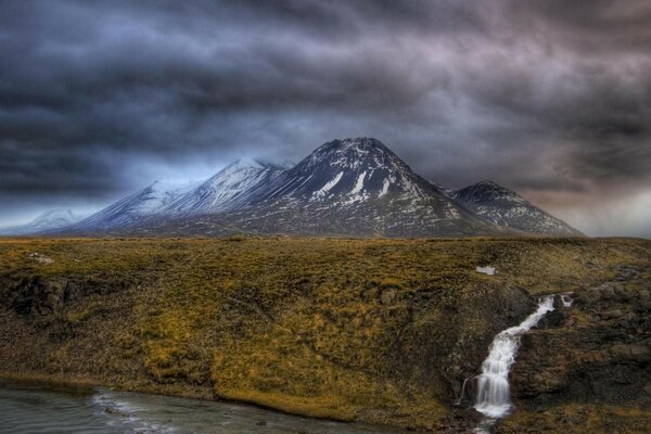 A mountain waterfall flows into the river