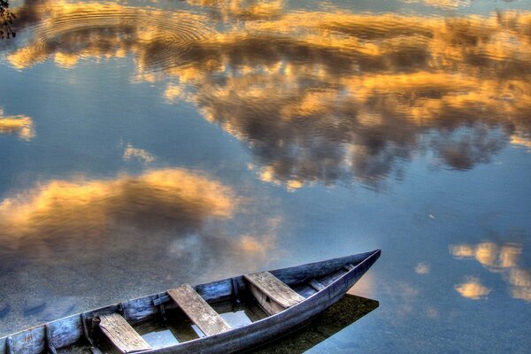 Boat on the background of the reflection of floating clouds