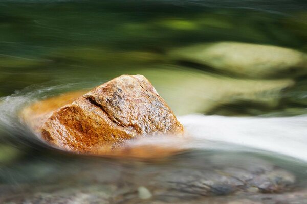 Большой камень в воде против потока