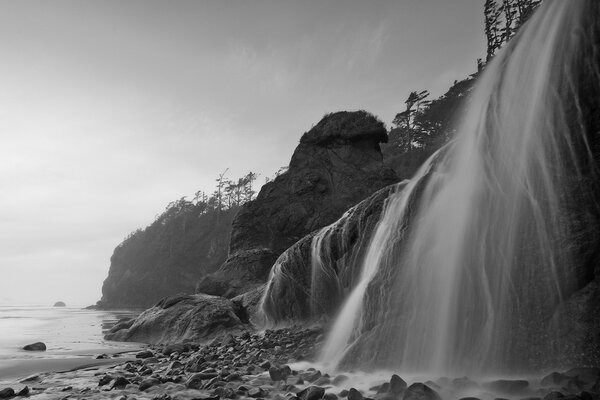 Einfarbiges Foto eines Wasserfalls, der auf die Steine fällt