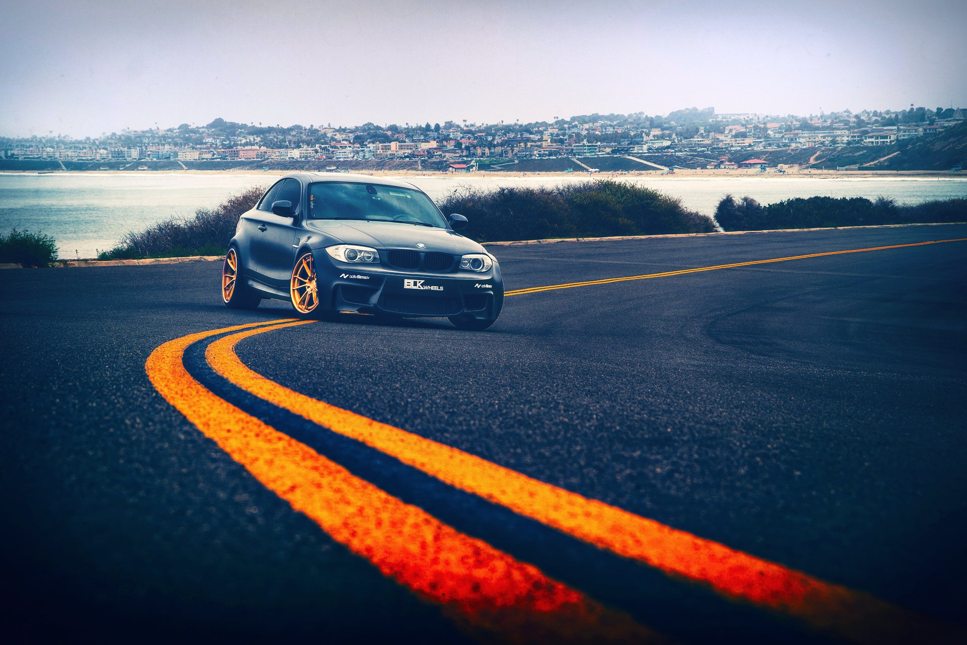 bmw 1 series m1 drives blk wheels road asphalt street signs marking town sea away