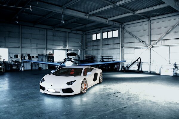 Hangar with an airplane and a white lamborghini