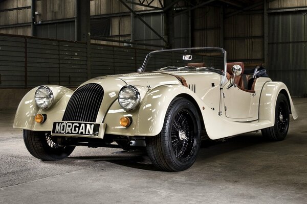 A white Morgen roadster in an iron hangar