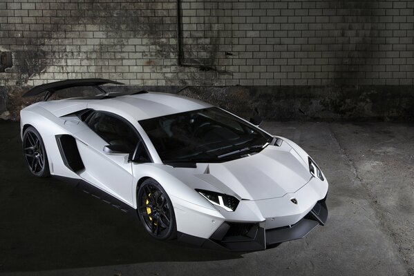 Coche Lamborghini blanco contra una pared de ladrillo