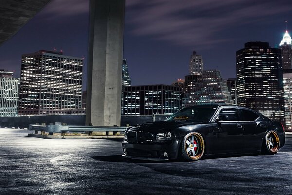 Czarny Dodge na tle nocnego miasta