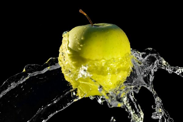 Żółte jabłko w rozpryskach wody