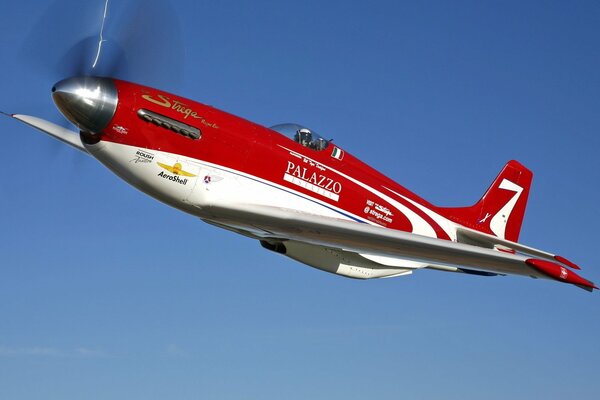 A sporty red -and-white airplane in the sky