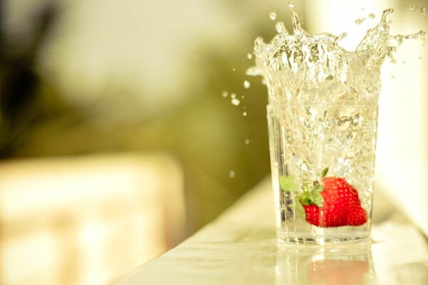 Fraises avec des éclaboussures tombe dans le verre