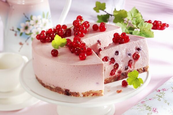 Rosa Käsekuchen mit roten Johannisbeeren auf dem Tisch