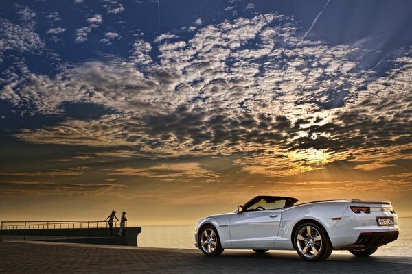 Chevrolet Camaro convertible blanco en el fondo de la puesta de sol