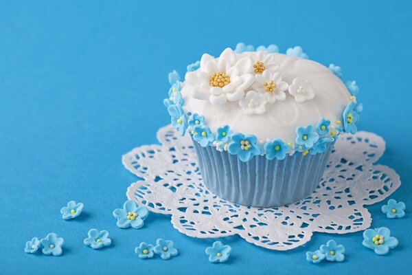 Cupcake con decoraciones en forma de flores sobre un fondo azul