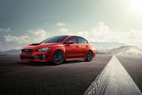 A red Subaru on an empty asphalt road through the mountains