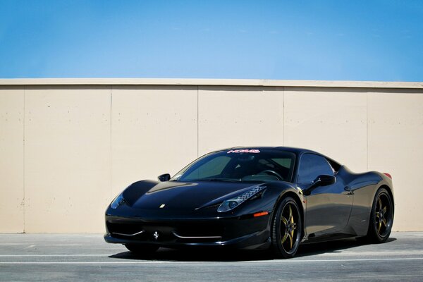 Black Ferrari in the parking lot by the wall
