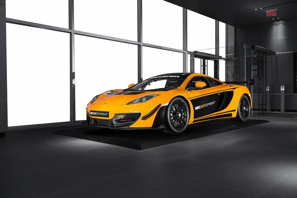 Pomarańczowy samochód mclaren mp4-12C gt stoi w pomieszczeniu