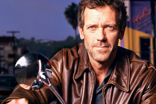 Hugh Laurie in giacca di pelle su una moto