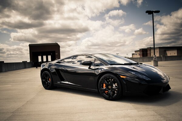 Schwarzer Lamborghini auf dem Hintergrund der schwebenden Wolken