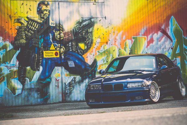 Blue tuned BMW on the background of a wall with graffiti