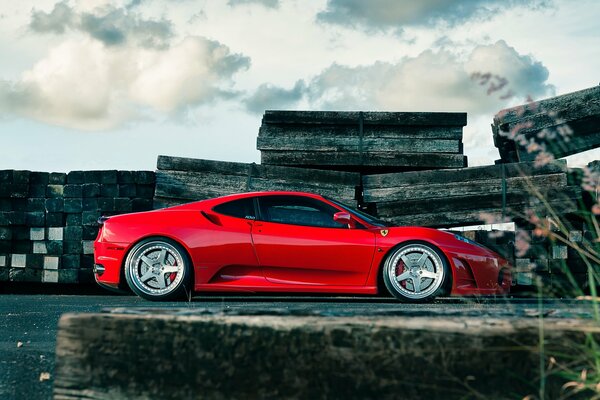 Roter Ferrari f430 mit Leichtmetallrädern vor dem Hintergrund von Himmel und Wolken