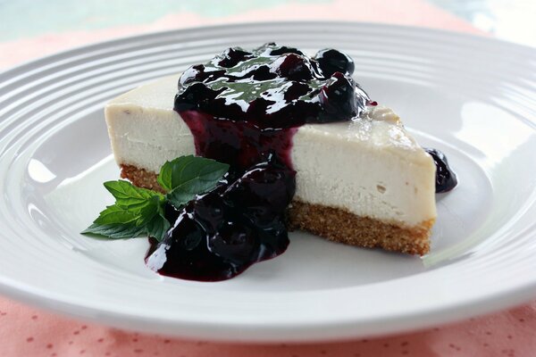 Tranche de gâteau au fromage avec confiture de cerises et feuille de menthe