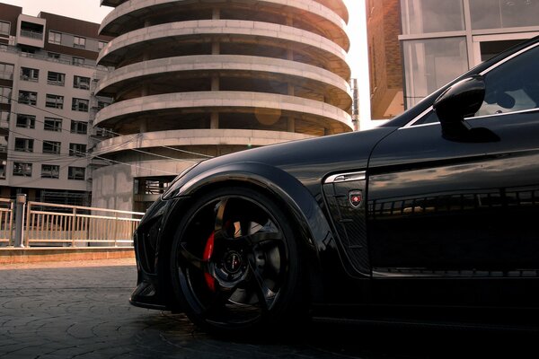 Black Porsche panamera on the background of a building of unusual design