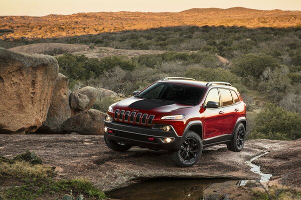 CHEROKEE JEEP AUF STEINEN BEI SONNENUNTERGANG