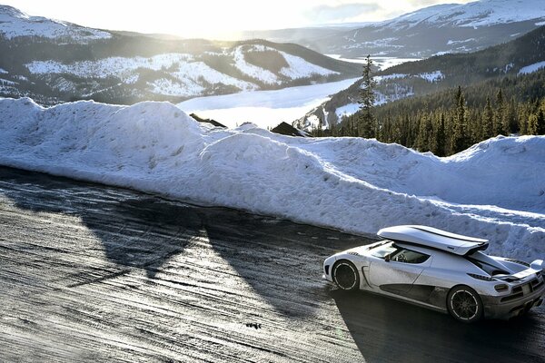 Il bianco Koenigsegg Agera corre lungo una strada innevata in montagna