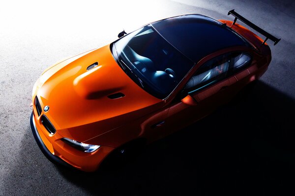 An orange BMW stands on a black background