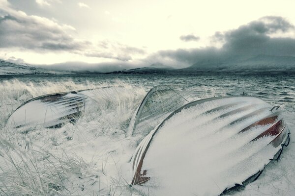 Overturned snow-covered boats near the shore