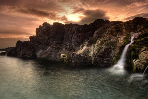 Wasserfall zwischen den Felsen bei Sonnenuntergang