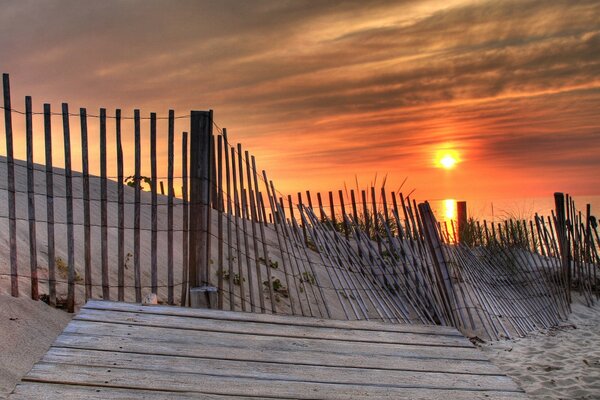 Sonnenuntergang vor dem Hintergrund eines fallenden Zauns