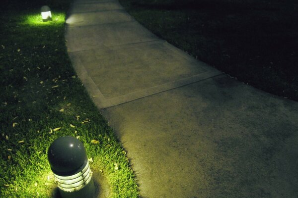 Ein Gartenweg auf dem Rasen, der mit Laternen beleuchtet ist