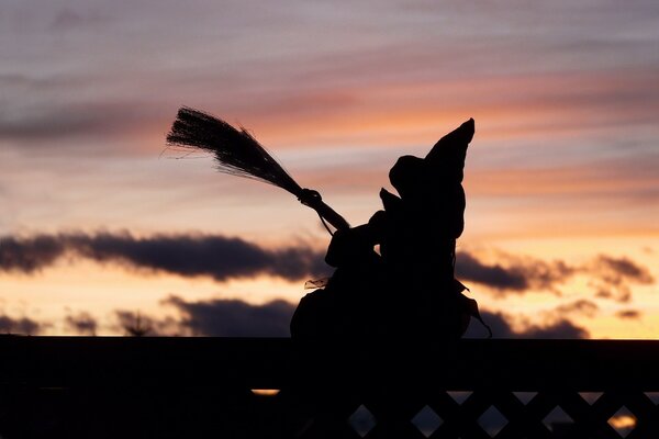 Statuetta di una strega su una scopa contro il cielo