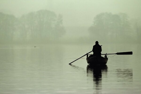 Niebla en el lago. pescador en barco