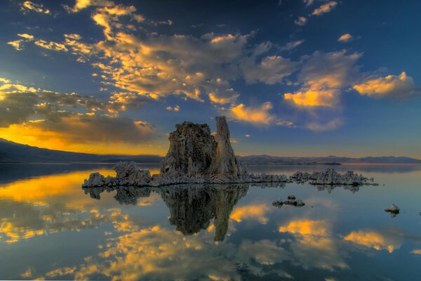 A rock in the middle of the sea at sunset