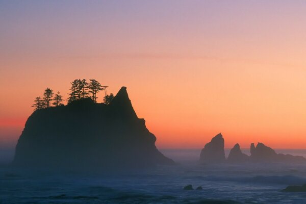 Red sunset over the waves of the sea and rocks sticking out of the water