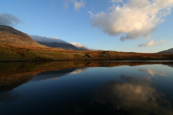 Reflexion des Himmels im Wasser vor dem Hintergrund der Berge